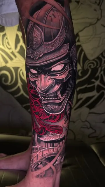 Máscara de samurai com detalhe em vermelho, na perna